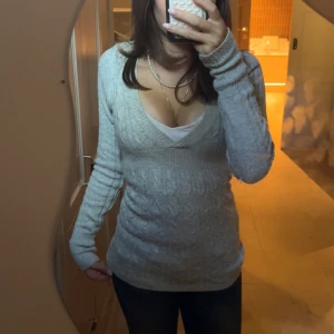 Höstig stickad babydoll tröja - Säljer en ljusgrå stickad tröja med v-ringning och lång ärm. Enkel att match med jeans eller kjol för en höstig outfit. Köpte tröjan här och vet därför inte tyvärr märket.