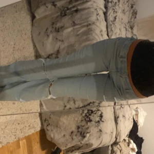 Bootcut ljusblå jeans med hål - Säljer ett par ljusblå jeans med bootcut passform och snygga hål vid knäna. Jeansen har klassisk femficksdesign, normal midja och är tillverkade i jeansmaterial. De är stretchiga så de passar från xxs-s.