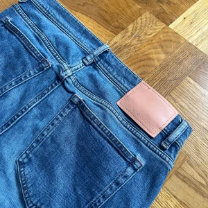 Blå skinny jeans från Acne Studios - Snygga blå jeans från Acne Studios med klassisk femficksdesign och skinny passform. Jeansen har hög midja, raka ben och är gjorda i mjukt denim med subtila slitningar. Perfekt för dig som gillar stilrena och tidlösa jeans med en modern touch.