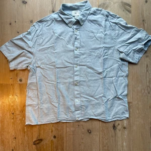 Ljusblå kortärmad skjorta från H&M - Snygg ljusblå skjorta från H&M i storlek L. Skjortan har klassisk krage med knappar, bröstficka och korta ärmar. Jag har själv sytt upp den lite så den passar någon som har M. Sitter kroppat och boxy, så som det ska va! Skriv vid intresse