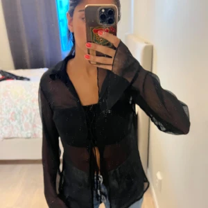 Svart transparent skjorta med snörning - Snygg svart blus som är genomskinlig.