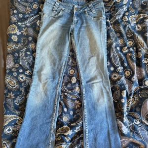 Bootcut jeans från Lee, ljusblå, 28/33 - Snygga ljusblå bootcut jeans från Lee i klassisk denim. Modellen har normal passform, fem fickor och bälteshällor. Materialet är bomull med lite elastan för extra komfort. Slitna detaljer vid benslut ger en cool vibe.