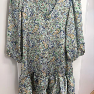 Blommig kortklänning från Zara - Säljer en superfin kortklänning från Zara med blommigt mönster i blått, grönt, beige och rosa. Passar perfekt inför sommaren💛