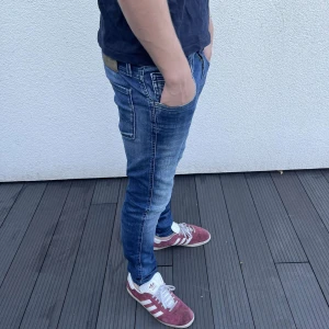 Replay Anbass skinny jeans blå - Snygga Replay Anbass jeans i blå tvätt med coola slitningar och kontrastsömmar. Modellen är skinny med låg midja och klassiska fem fickor. Jeansen har en modern look och är gjorda i stretchigt denim för skön passform.