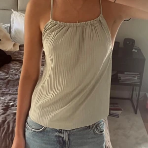 Ljusgrön plisserad linnetopp - Säljer en ljusgrön linnetopp med tunna axelband som korsas i ryggen. Toppen har plisserad struktur och är ärmlös med en lite loose passform. Perfekt för varma dagar och enkel att styla med jeans eller kjol. OBS Alla kläder tvättas innan de skickas!💕