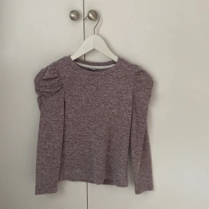 Lila långärmad tröja Lindex - Säljer en Lila långärmad tröja från Lindex med puffade axlar. Tröjan har en mjuk och skön känsla, perfekt för dig som gillar enkel stil med en twist. Passar dig som vill ha något bekvämt men ändå snyggt.