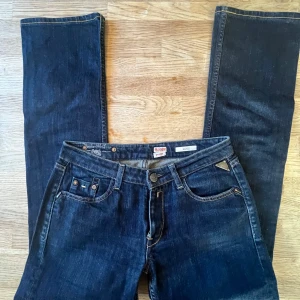 Replay mörkblå jeans med broderi - Snygga mörkblå jeans från Replay med klassisk femficksdesign och coolt broderi på bakfickorna. Byxorna har raka ben, kontrastsömmar och en unik Replay-plakett bak i midjan. Passar dig som gillar stilrena jeans med detaljer.