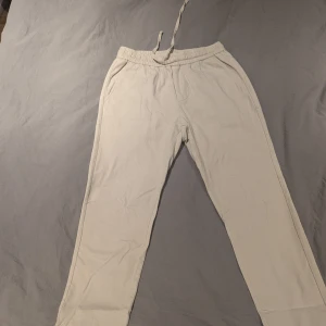 Beiga linne byxor Only & Sons - Snygga beiga linne byxor från Only & Sons med elastisk midja och dragsko. Byxorna har en avslappnad passform, sidofickor och en bakficka. Perfekta för chill dagar eller när du vill vara bekväm men ändå se fräsch ut.