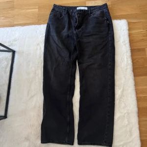 Svarta straight jeans från Bershka - Säljer ett par svarta jeans från Bershka i storlek 42. Modellen har raka ben och klassisk femficksdesign med bälteshällor. Jeansen är tillverkade i ett mjukt denimtyg och har en enkel, stilren look som funkar till många olika outfits.