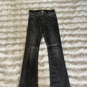 Bootcut svarta jeans med vita sömmar - Snygga svarta jeans med bootcut passform och vita kontrastsömmar. Klassisk femficksmodell med knapp och dragkedja fram. Jeansen har en lätt tvättad look och är tillverkade i mjukt denimtyg som sitter skönt hela dagen.