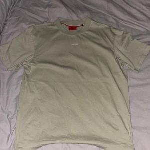 Militär grön t-shirt från Hugo Boss - Snygg militär grön t-shirt från Hugo Boss med diskret HUGO-tryck på bröstet. Klassisk rund hals och korta ärmar. Nypris 800kr och använd minst 1 gång vid snabb affär kan jag gå ner i pris