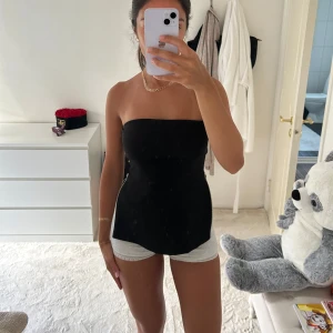 Svart tubtopp med dragkedja i sidan - Säljer en svart tubtopp med stilren bandeau-look och cool dragkedjedetalj i sidan.