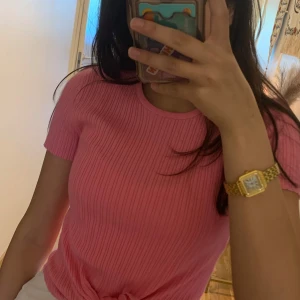 Rosa ribbad topp med knyt från F Sister - Superfin rosa ribbad topp från F Sister med korta ärmar och rund hals. Toppen har en snygg knytning framtill som ger en trendig look. Perfekt att styla med jeans eller kjol för en färgglad outfit.