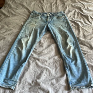 Ljusblå tapered jeans från H&M - Säljer ett par ljusblå jeans från H&M med relaxed fit och tapered ben. Jeansen har justerbar midja, klassiska fem fickor och snygga slitningar för en chill vibe. Perfekta för dig som gillar en avslappnad stil och vill ha bekväma jeans i bomull. Storlek 158    