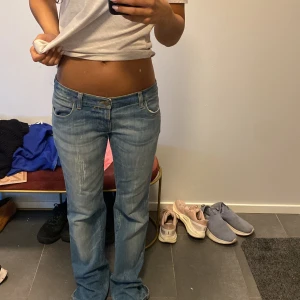 Blå bootcut jeans med låg midja - Säljer ett par blå jeans med snygg bootcut och låg midja. Jeansen har klassiska fem fickor, coola detaljer på bakfickorna och slitningar framtill för en chill vibe. Perfekta om du gillar retrostil och vill ha ett par jeans som sticker ut. Finns ingen storlek jag kan se då den har flagnat och är köpta på vinted, men de passar en storlek M ungefär och ni kan jämföra med hur den sitter på mig💕 endast nedtrampade annars inga defekter. Skriv vid frågor💕