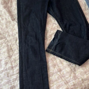 Mörkblå jeans från GANT W29/L34 - Snygga mörkblå jeans från GANT med klassisk femficksdesign och broderade bakfickor. Modellen har normal midja och smal passform, perfekt för dig som gillar stilrena och tidlösa jeans. Materialet är slitstarkt denim med kontrastsömmar.