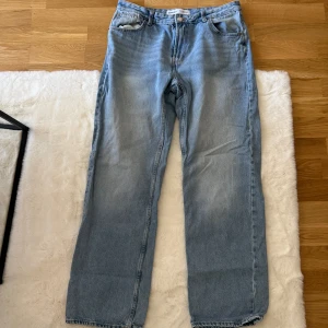 Ljusblå raka jeans från Bershka - Säljer ett par ljusblå jeans från Bershka med klassisk femficksdesign och raka ben. Jeansen har normal passform och är tillverkade i bomull. Perfekt för dig som gillar en enkel och clean look med lite retrovibe.