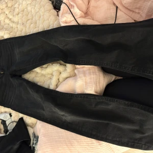 Svarta bootcut jeans med fickdetaljer - Säljer ett par svarta jeans med snygga fickor med lock och knapp bak. I mycket fint skick och pass form 