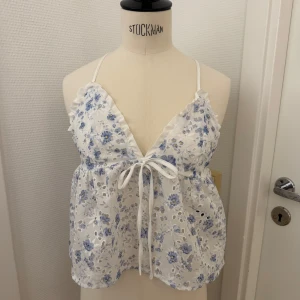 Blommig vit och blå topp med knyt - Supersöt topp i vitt med blått blommigt mönster och tunna axelband som korsas i ryggen. XS. Luftig & lätt. Snygg till jeans! Kan hämtas på Hägerstensåsen i Stockholm 🌸