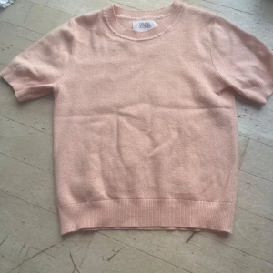 Orange rosa stickad topp från Zara - Superfin ljusrosa stickad topp från Zara med korta ärmar och rund halsringning. Mjuk och skön kvalitet, perfekt till jeans eller kjol. Enkel och stilren design som är lätt att matcha.
