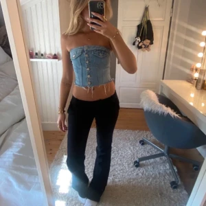  jeans topp - Säljer en ljusblå bandeau tubtopp i jeansmaterial med snygga silverfärgade knappar framtill och fransig kant nedtill. Toppen är axelbandslös och croppad, perfekt för dig som vill ha en cool och trendig look.