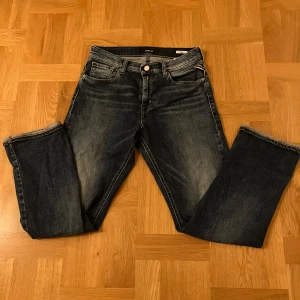 Replay Thad mörkblå jeans - Snygga mörkblå jeans från Replay, modell Thad. Klassisk femficksdesign med raka ben och normal passform. Jeansen har coola slitningar och är tillverkade i robust denim som ger en schysst streetkänsla. Perfekta för dig som gillar stilrena och tidlösa jeans.