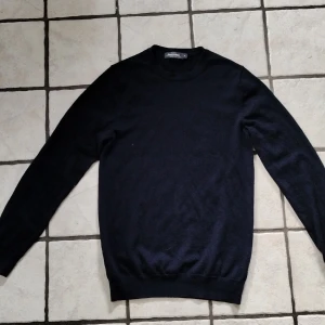 Mörkblå merinoullströja från Dressmann - Säljer en klassisk mörkblå tröja från Dressmann i mjuk merinoull. Tröjan har rund halsringning och långa ärmar, perfekt för lager-på-lager eller som den är. Enkel och stilren design som passar till mycket.