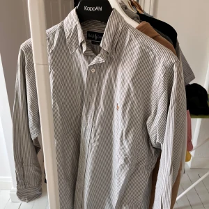 Ralph Lauren skjorta - Riktigt snygg Ralph Lauren skjorta som är grårandig. Skick 9/10, nån liten prick på magen som tas bort genom tvättmaskin, nypris 1300kr. Hör av dig vid funderingar 👍