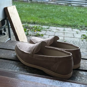 Beige mocka loafers från Old Money - Säljer ett par stilrena beige loafers från Old Money i mjuk mocka. Köpte dessa men de var för stora och försent att lämna tillbaka så säljer dom. Riktigt skön sula och riktigt fin sko men rekommenderar för storlek 45. Använda cirka 2-3 gånger därför är sulan lite skitig men ska se till att göra rent dom.