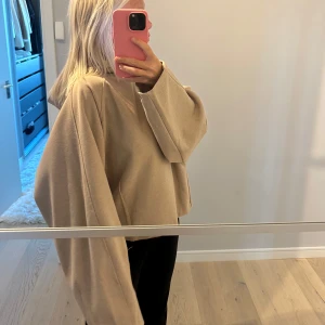 Beige oversized tröja - Säljer en beige oversized tröja med långa, vida ärmar och croppad passform. Perfekt för en avslappnad och trendig look. Tröjan är enkel och stilren, utan synliga detaljer eller mönster.
