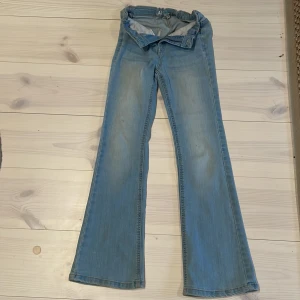 Ljusblå bootcut jeans från AB Industry - Säljer ett par ljusblå jeans från AB Industry i storlek 152. Byxorna har bootcut-modell med utsvängda ben och klassisk femficksdesign. Perfekta för dig som gillar en retroinspirerad look med bekväm passform.