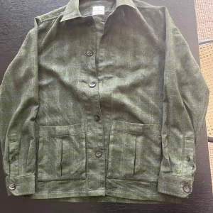 Grön rutig overshirt / flanellskjorta från John Henric - Säljer en grön rutig overshirt från John Henric. Jackan har stora fickor framtill, knäppning med knappar och klassisk krage. Perfekt lager-på-lager-plagg för dig som gillar stilrena detaljer. Riktigt skön tyvärr för liten skriv för mer info / bilder