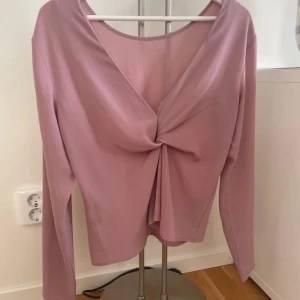 Gammaldagsrosa tröja med knyt i rygg - En fin gammaldags rosa tröja. Simpel framtill och baktill har den en knut. Från Nelly.