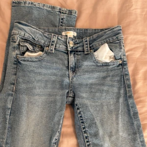 Blå jeansbyxor från Gina Tricot - Säljer ett par klassiska blå jeansbyxor från Gina Tricot i storlek 158. Byxorna har normal passform, raka ben och fem fickor med knapp- och dragkedjestängning. Perfekta för en avslappnad stil.
