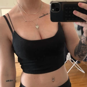 Svart croppad linnetopp - Säljer en svart croppad linnetopp med smala axelband. Toppen har en enkel och stilren design som passar perfekt till sommaren. Perfekt att matcha med höga jeans eller kjol.