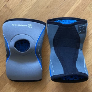 Grå-blå knäskydd från Rehband - Säljer ett par grå och blå knäskydd från Rehband.  De är i storlek XS och har 5 mm tjocklek. Perfekta för extra stöd vid träning eller aktivitet. Snygg design med svarta och blå detaljer.