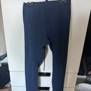 Mörkblå tights från OTI - Mörkblå tights med hög midja från OTI. De är tighta och har en enkel, stilren design utan synliga detaljer. Perfekta för träning eller vardagsaktiviteter.