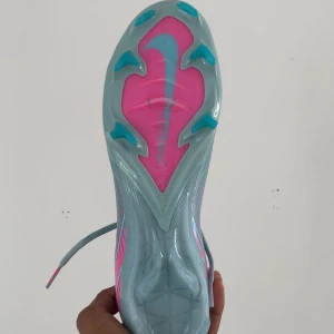 Nike Air Zoom Mercurial Vapor 16 ljusblå och rosa  - Säljer ett par Nike Mercurial fotbollsskor i ljusblått med rosa detaljer och sula. Skorna har snörning och är designade för maximal fart och grepp på planen. Perfekta för dig som vill sticka ut med stil på fotbollsplanen.