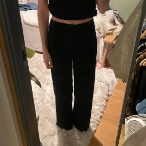 Svarta kostymbyxor från Bershka - Säljer ett par svarta kostymbyxor från Bershka med hög midja och vida ben. Kanten är uppsydd med hjälp av vilisofix.