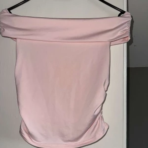 Ljusrosa offshoulder topp - Säljer en ljusrosa offshoulder topp i mjukt och stretchigt material. Toppen är axelbandslös. Har aldrig blivit andvänd!💕