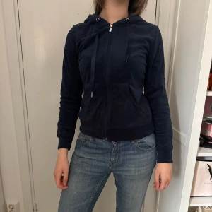 Mörkblå hoodie med dragkedja - Säljer en mörkblå hoodie med dragkedja och huva. Tröjan har långa ärmar, fickor framtill och ribbade muddar vid ärmslut och nederkant. Perfekt för en avslappnad stil.