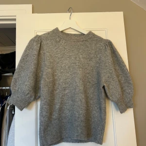 Grå stickad tröja från H&M - Mysig grå stickad tröja från H&M med rund halsringning och ribbade muddar. Tröjan har en något lös passform och är perfekt för kyligare dagar. Enkel och stilren design som passar till mycket.