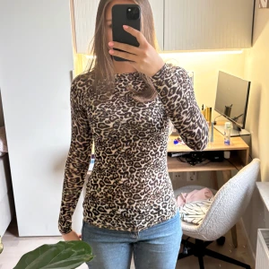 Leopardmönstrad långärmad topp - Säljer en tight långärmad topp med leopardmönster. Toppen har rund halsringning och är i ett stretchigt material som sitter figurnära. Perfekt för dig som gillar djurmönster och vill sticka ut.