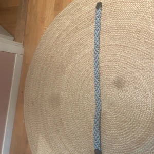 Flätat ljusblått bälte - Säljer ett smalt flätat bälte i ljusblått med detaljer i mörkare färg vid ändarna. Perfekt för att ge en extra touch till jeans eller klänning. Bältet har en enkel och stilren design.