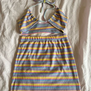 Randigt sommar sett - Säljer ett sött ribbat sommar sett med halterneck och färgglada ränder i pastell.  Settet har en kroppsnära passform, perfekt för varma dagar. Mjukt och stretchigt material som sitter väldigt bekvämt.