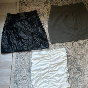 Tre kjolar från SHEIN i olika material - Säljer tre snygga kjolar från SHEIN: en svart kjol i skinnimitation, en grå figurnära kjol och en vit kjol med rynkade detaljer. Perfekta för att skapa olika looks och passar till många tillfällen.