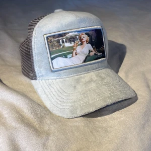 Ljusgrå keps med vintage-inspirerad bild från Maggiore - Snygg ljusgrå keps med mesh på sidorna och en stor vintage-inspirerad bild framtill. Märket Maggiore syns på sidan. Perfekt accessoar för en cool och avslappnad stil. OANVÄND!!!