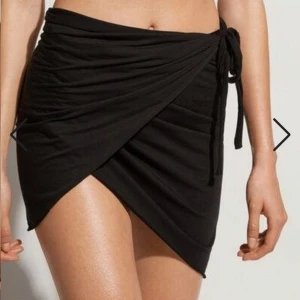 Calsedonia wrap around svart sarong - Stl är One size då man kan anpassa hur man vill ha den. Oanvänd inköpt på Zalando. Svart kort wrap around sarong från Calsedonia. Kan användas som kjol eller sarong. 