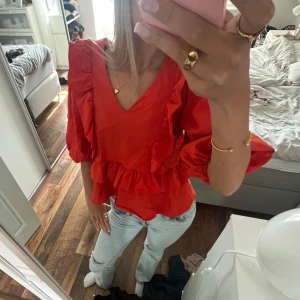 Röd blus med volanger från ellos. - Bra skick, knappt använd. Fin färg både nu i sommar/vår men även till vintern. Storlek 34.
