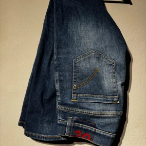 Dondup jeans - Säljer ett par klassiska blå jeansbyxor med raka ben och normal passform. Byxorna har fem fickor, kontrastsömmar och en liten röd detalj vid benslutet. Perfekta till vardags och passar till det mesta.